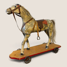Load image into Gallery viewer, Ziebarth's Antiques vintage wooden pull toy horse with weathered finish, leather saddle, and metal wheels on platform.