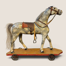 Load image into Gallery viewer, Ziebarth's Antiques vintage wooden pull toy horse with weathered finish, leather saddle, and metal wheels on platform.